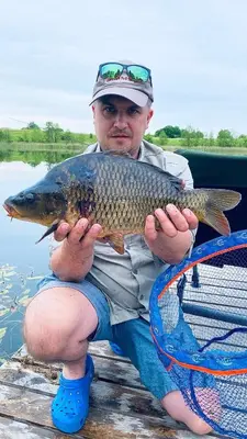 a man sitting on a dock holding a fish at Pineplace twins NIDA in Žaugėdai