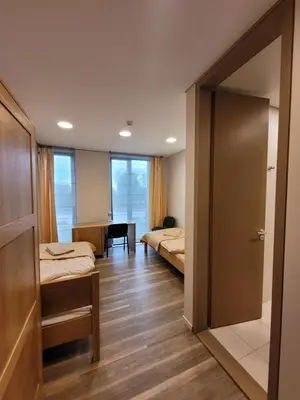 a room with two beds and a door to a bedroom at Jono Pauliaus II piligrimu namai in Raseiniai