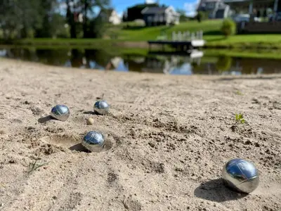 a group of balls in the sand next to a lake at Gandro lizdas in Lekėčiai