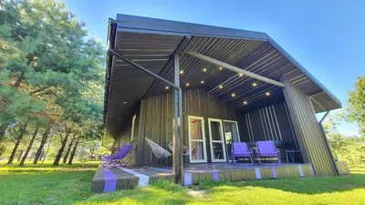 a small house with purple chairs on the porch at Kaimo turizmo sodyba Geras in Leliūnai