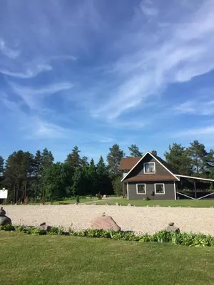 a house sitting on a beach next to a yard at Kaimo turizmo sodyba Geras in Leliūnai