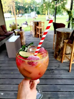 a person holding a drink with a striped straw at Natur Camp Birštonas Small Cabins in Birštonas
