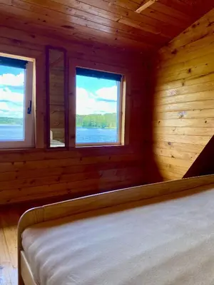a bedroom with two windows in a log cabin at Poilsiadienis in Aukštadvaris