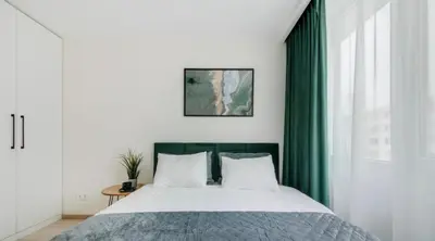 a bedroom with a large bed with green curtains at Zveryno apartment in Vilnius