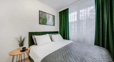 a bedroom with a large bed with green curtains at Zveryno apartment in Vilnius