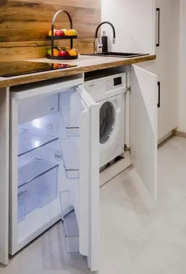 a kitchen with a washer and dryer under a counter at Zveryno apartment in Vilnius