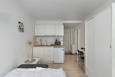 a small kitchen with white cabinets and a white refrigerator at Pramonės Apartment #7 by PoloApartments in Kaunas