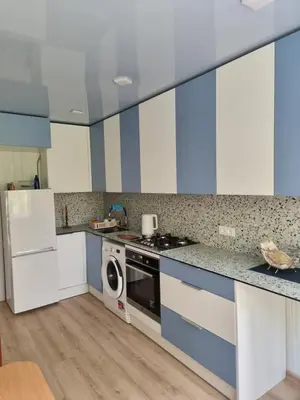 a kitchen with blue and white cabinets and a washer at Kaunas 174 in Murava