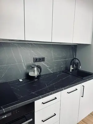 a kitchen with white cabinets and a black counter top at Sunny loft 24x7 x free parking x close to old town by H&H in Vilnius