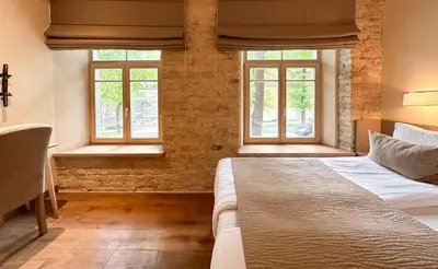 a bedroom with a bed and two windows at New Town Home in Vilnius
