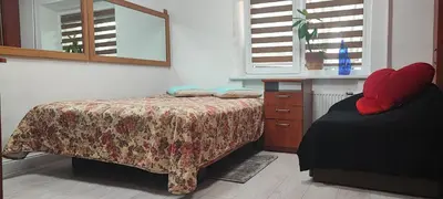 a bedroom with a bed and a dresser and windows at Honey Apartament in Druskininkai