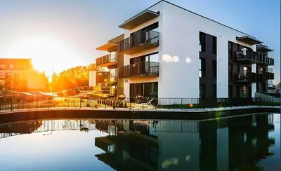 a building with a reflection in a body of water at Gilužio Apartments in Vilnius