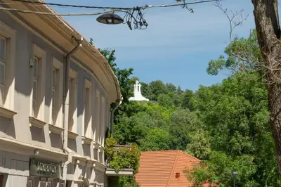 a building with a tower in the background with trees at Old Town Hideaway in Vilnius