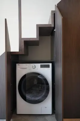 a washing machine in a kitchen with a staircase at K32 Loft in Vilnius