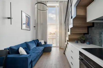 a living room with a blue couch in front of a window at 60 Loft in Vilnius