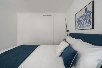 a bedroom with a white bed with a blue headboard at Loft 60 with Free parking in Vilnius