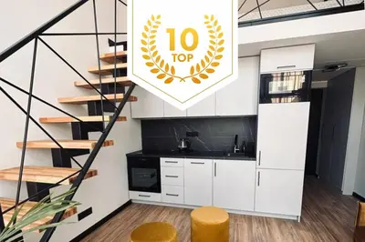 a kitchen with white cabinets and a spiral staircase at Sunny loft 3 x 24x7 x Close to old town in Vilnius