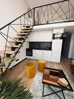a living room with a spiral staircase and yellow stools at Sunny loft 3 x 24x7 x Close to old town in Vilnius
