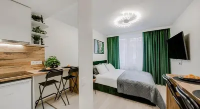 a bedroom with a bed and a desk and a kitchen at Green Apartment in Vilnius
