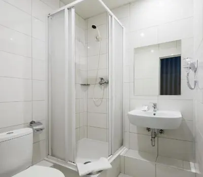 a white bathroom with a shower and a sink at Naujamiescio Studio 305 in Vilnius