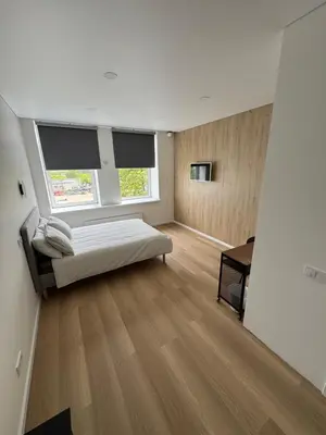 a bedroom with a bed and a desk and two windows at 10 New Airport Apartment in VNO