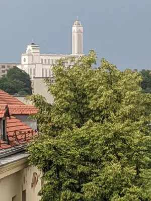 a tree in front of a building with buildings in the background at Tiny Studio Apartment in Kaunas