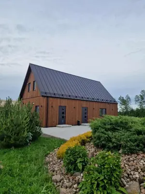 a large wooden barn with a black roof at Baltasis beržas