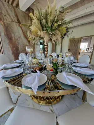 a dining room with a table with white chairs and a centerpiece at Baltasis beržas