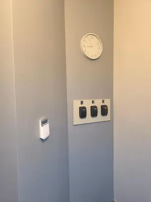 a clock on a wall next to a wall with switches at Studio 2 in Utena