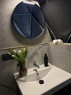 a bathroom sink with a round mirror above it at Tyla dviese in Kaciūniškiai