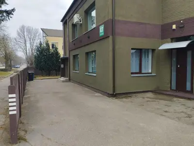 a green building with a sidewalk in front of it at XL apartamentai su nemokamu parkingu in Šiauliai