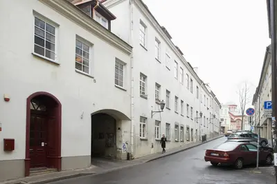 a person walking down a street next to a white building at Apartments in old town Latako Street in Vilnius