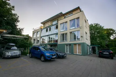 a building with three cars parked in a parking lot at Mini dvivietis Free parking in Vilnius