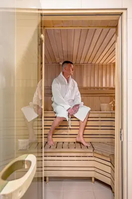 a man sitting in a sauna in a bath tub at HOME Apart-Hotel Vilnius in Vilnius