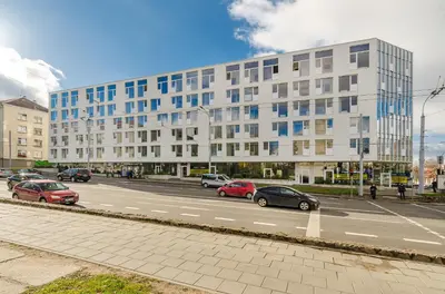a street with cars parked in front of a large building at City Studio 1A - Courtyard View in Vilnius