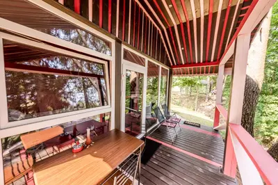 a screened in porch of a house with a wooden table at VIP Yellow dream house Sodyba Geras geltona žalia raudona violetinė in Anykščiai