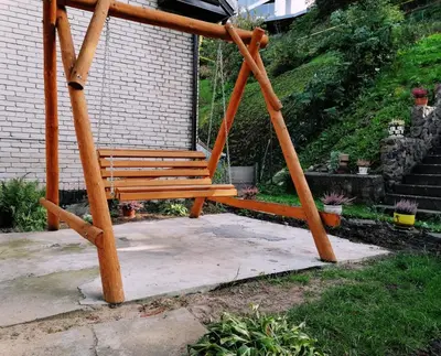a wooden swing sitting in front of a building at Chill&Go Premium in Kaunas