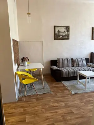 a living room with a couch and a table and yellow chairs at Gediminas apartment in Kaunas