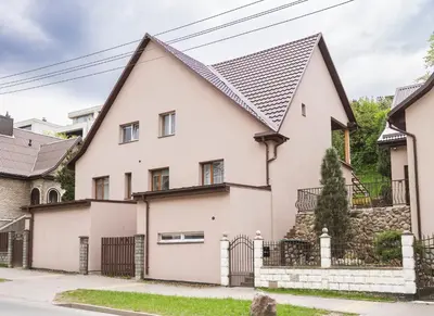 a white house with a black roof at Groundfloor Apartment on the Green Hill in Kaunas
