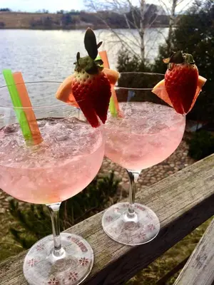 two glasses with strawberries in them sitting on a wooden rail at Gilužio Rivjera in Vilnius