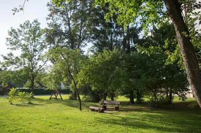 a park with two benches and trees and a playground at Sonatina apartment in Druskininkai