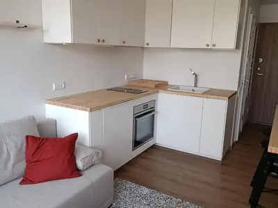 a small kitchen with white cabinets and a couch at Stylish Studio in Central Vilnius in Vilnius