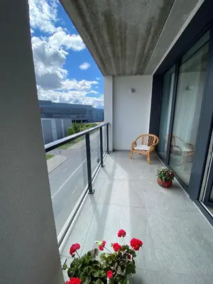 a balcony with red flowers and a chair on a building at J. Ralio apartamentai (monkey) in Vilnius