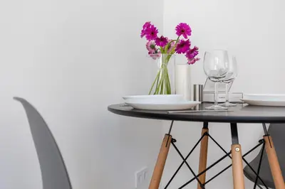 a table with glasses and a vase of purple flowers at River To The City - Self check in in Vilnius
