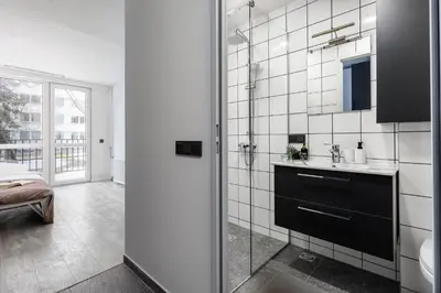 a bathroom with a sink and a glass shower door at River To The City - Self check in in Vilnius